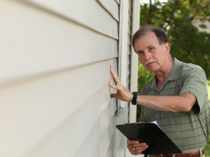 Homeowner inspecting roof and siding before winter