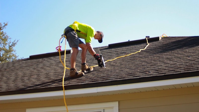 A roofer inspecting a residential shingle roof