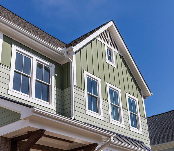 Low angle view of a residential home with green colored vinyl siding